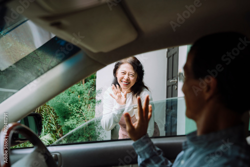 Happy senior woman waving hand to say goodbye to her husband at front door. © THESHOTS.CO