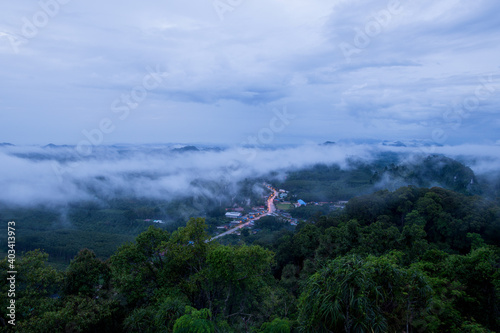 Mountain range with visible silhouettes through the morning colorful fog with cloud sky
