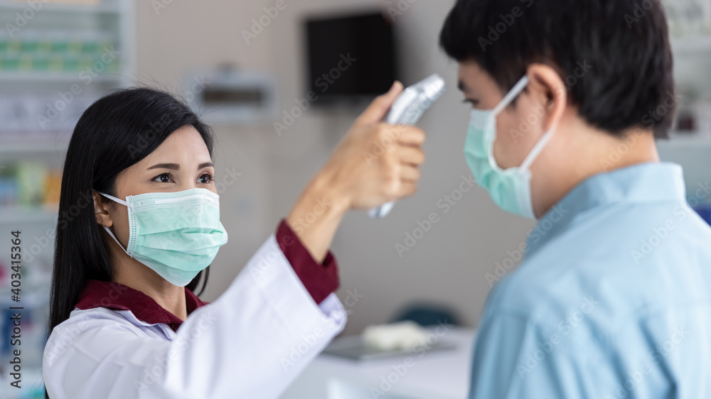 Asian Female pharmacists measure the fever before visiting the drugstore Thailand close up and selective focus corona virus covid-19 concept