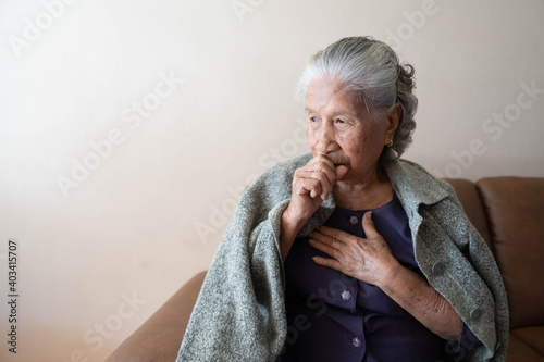 Asian senior ill female have a cough and sore throat. Causes of cough include common cold, flu, respiratory tract infection, pneumonia, bronchitis, allergy or asthma. Elderly health care concept.