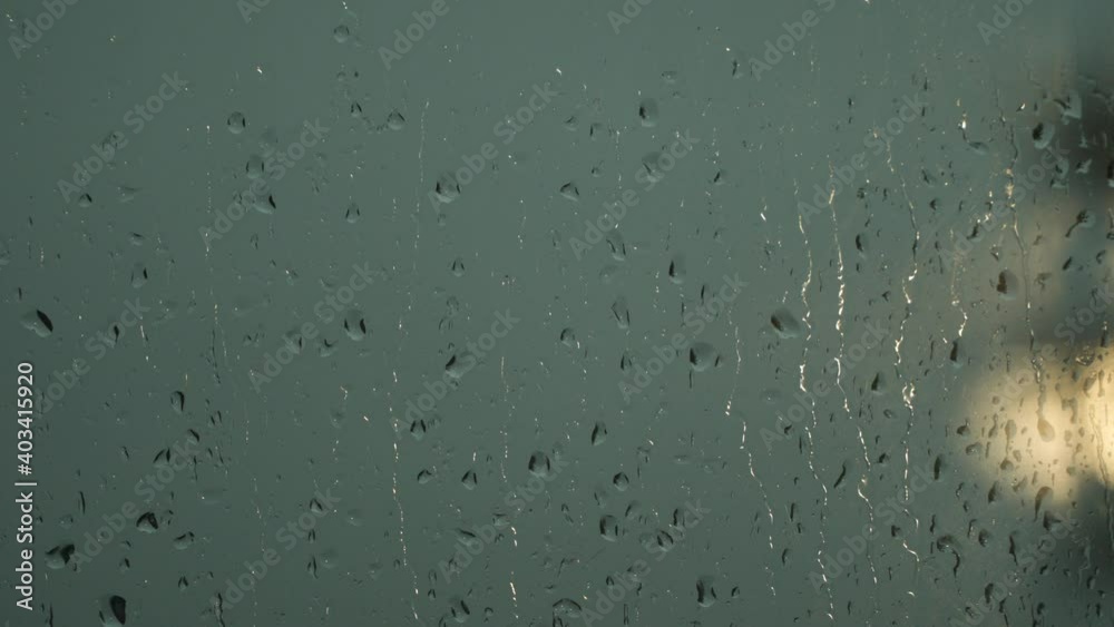 Raindrops on the window pane. A lantern can be seen outside the window. Natural background
