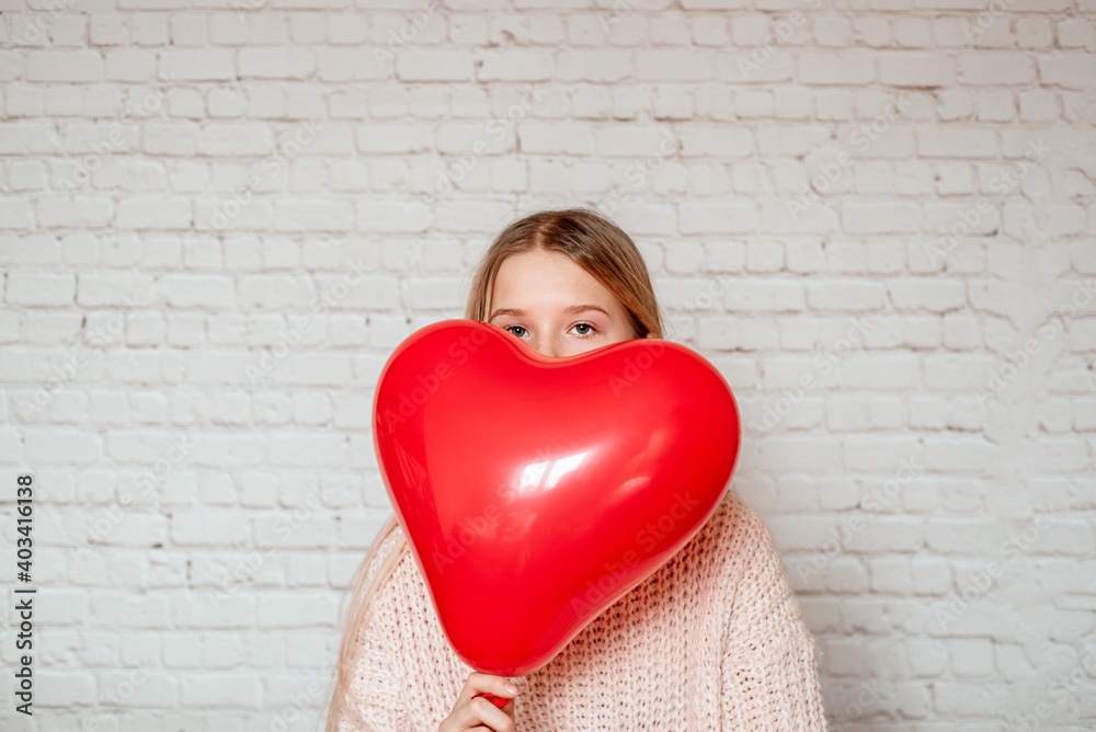 Portrait of a girl peeking out from behind big red heart shaped balloon Portrait of a girl peeking out from behind big red heart shaped balloon