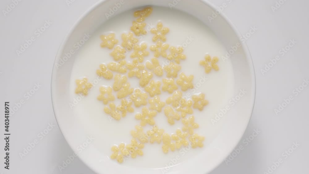 Kid corn flakes in a milk in a white bowl, top view Kid corn flakes in a milk in a white bowl, top view