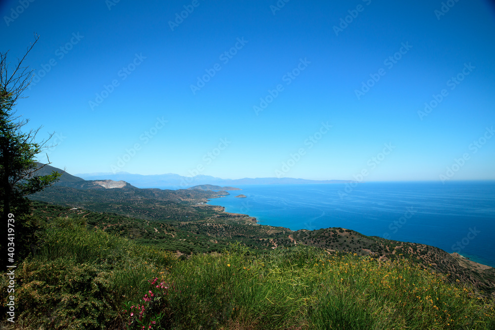 A wonderful view of the island-blue sea, sky, mountains, trees and flowers.
