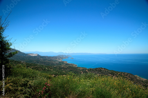 A wonderful view of the island-blue sea, sky, mountains, trees and flowers.
