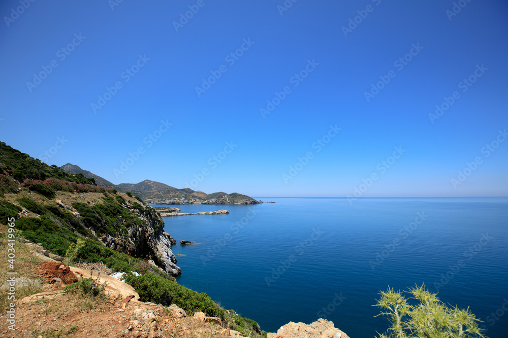 A view of the beautiful island is the blue sea and sky, green mountains and plantations of olive trees.