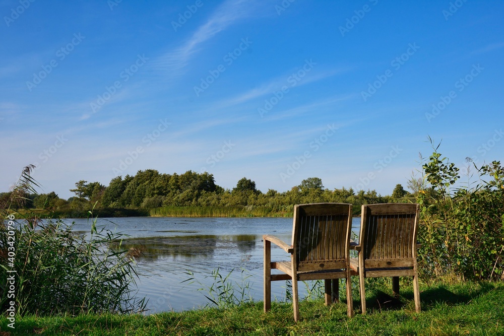 relaxation scenery, two chairs invites to take a rest next to pond at summer and blue sky relaxation scenery, two chairs invites to take a rest next to pond at summer and blue sky