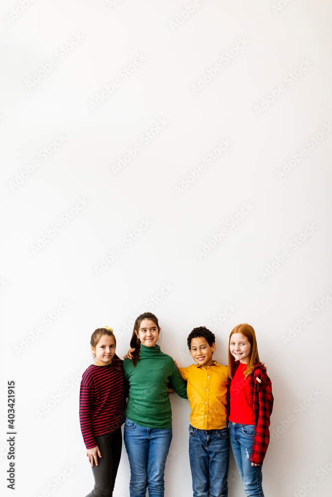 Portrait of cute little kids in jeans looking at camera and smiling, standing against white wall Portrait of cute little kids in jeans looking at camera and smiling, standing against white wall