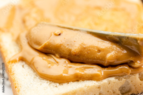 Crunchy peanut butter spreading on a toast © ansyvan