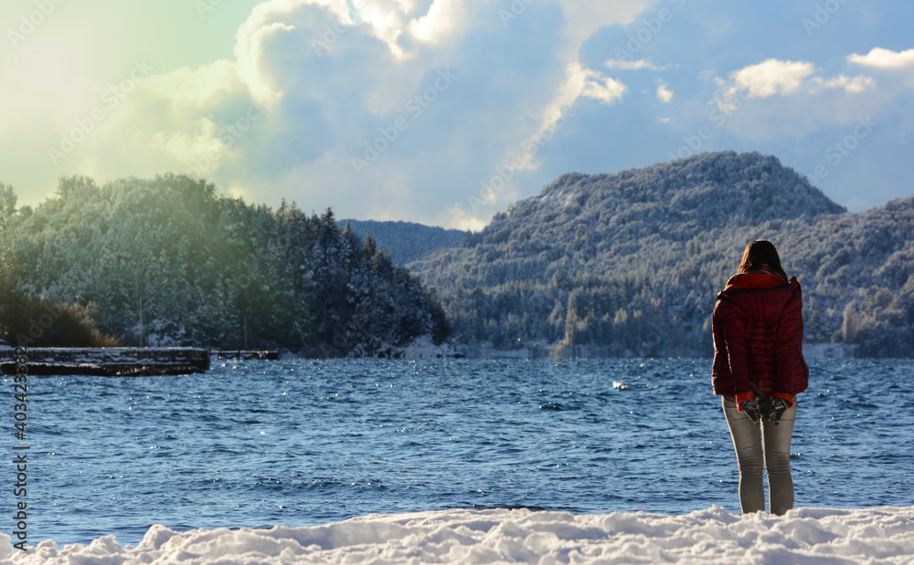 young woman on the shore of a lake, with all the snowy landscape