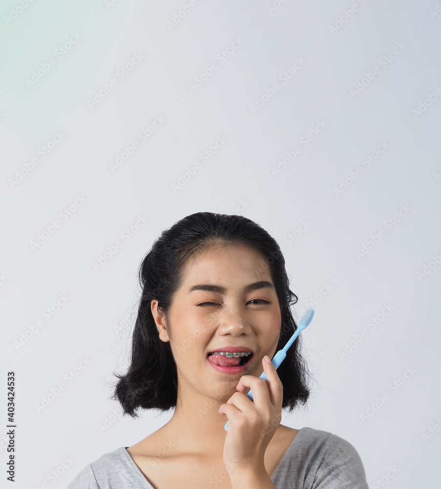 Dental brace teenager girl smile holding toothbrush and looking to camera. white teeth with blue braces. Dental care. Asian woman with contact lens and orthodontic accessories. Cosmetic dentistry. Dental brace teenager girl smile holding toothbrush and looking to camera. white teeth with blue braces. Dental care. Asian woman with contact lens and orthodontic accessories. Cosmetic dentistry.
