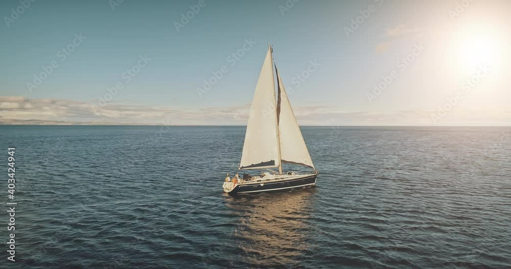 Sailing yacht race at sun light aerial. Yachting on serene seascape at open sea. Boat with big white spinnaker sail at ocean bay. Lonely ship cruise at water on summer sunny day. Cinematic drone shot Sailing yacht race at sun light aerial. Yachting on serene seascape at open sea. Boat with big white spinnaker sail at ocean bay. Lonely ship cruise at water on summer sunny day. Cinematic drone shot