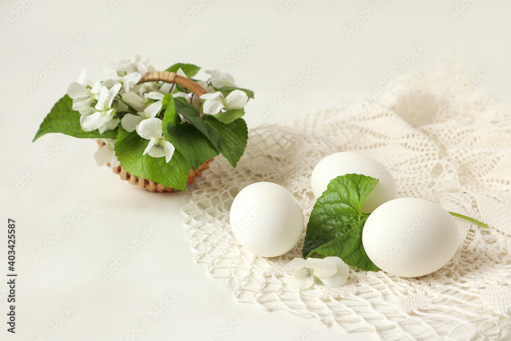 White chicken eggs on a white openwork napkin with a delicate bouquet - the concept of celebrating the bright holiday of Easter
