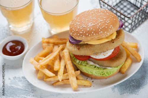 White plate with double fishburger, french fries and beer over white concrete background, studio shot