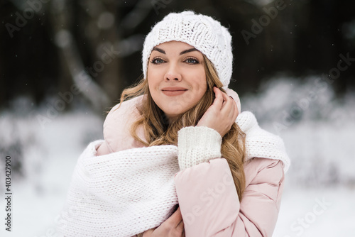 in a snowy forest, a beautiful girl smiles in a light hat and a trigger. portrait