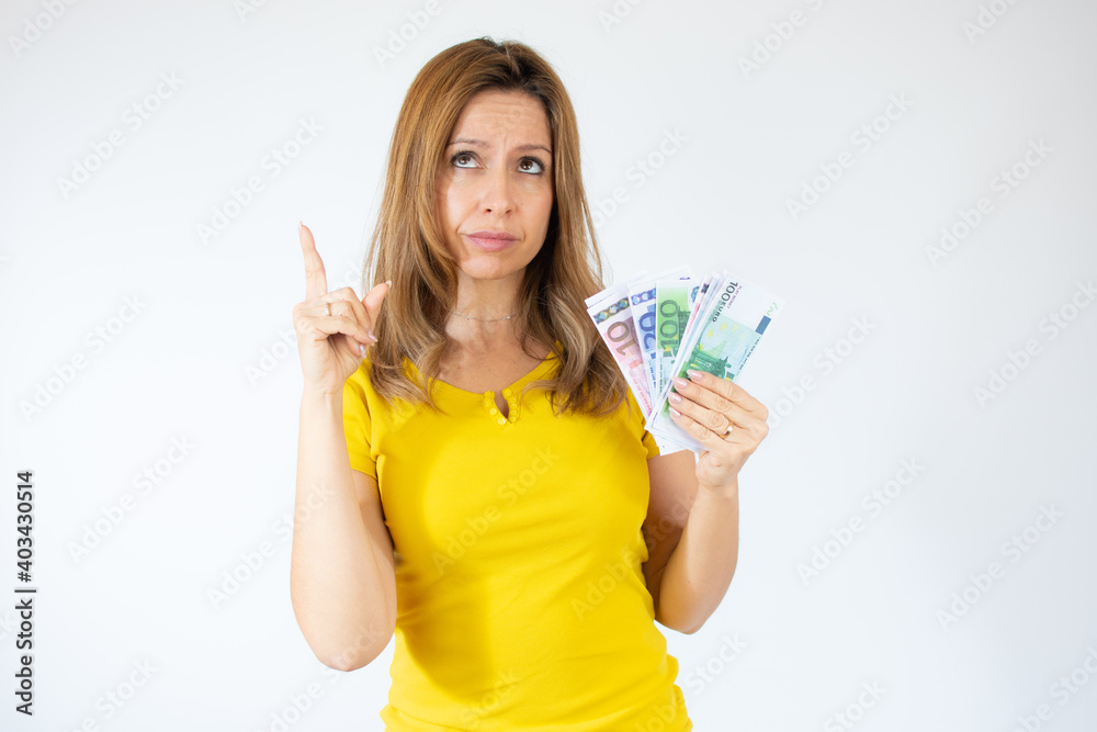 Portrait of a young woman thinking holding money banknotes and celebrating isolated over white background Portrait of a young woman thinking holding money banknotes and celebrating isolated over white background