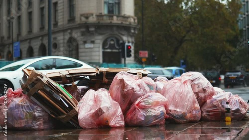 Cardboard and pink plastic bags of garbage on the sidewalk