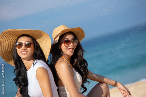 Two happy women are sitting on the beach While relaxing on vacation for the weekend on sunny days and nice weather in travel and holiday concept.