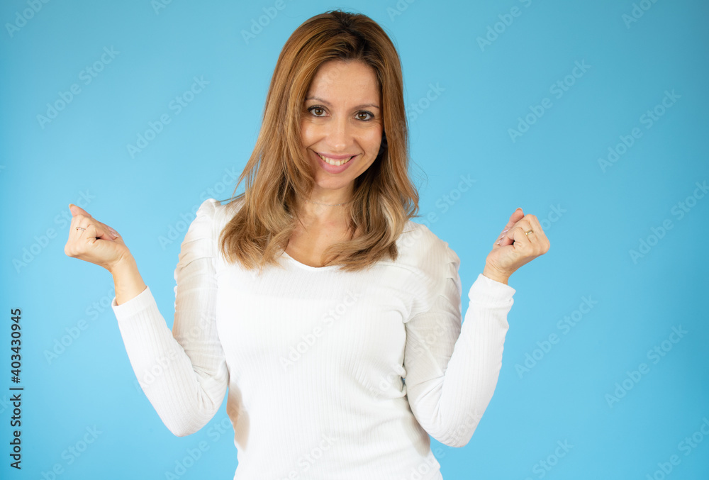 Surprised happy caucasian woman in sweater and looking at the camera over blue background Surprised happy caucasian woman in sweater and looking at the camera over blue background