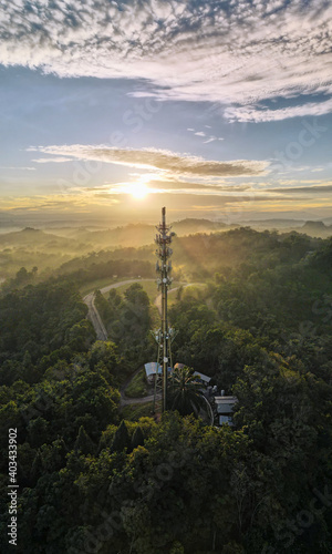 Panorama Aerial view of 5G Communication tower during beautiful sunrise with clouds, mists and fog