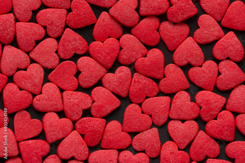 Red Hearts Candy on black surface close up. Valentine's day concept. Macro. Sweet red candy texture