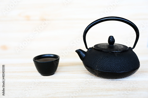 Black teacup and teapot on wooden table