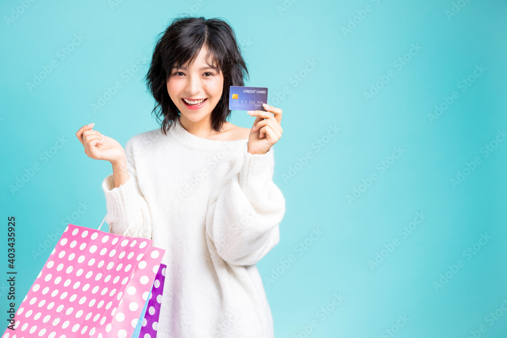 Young woman holding shopping bags presenting credit card in her hand Young woman holding shopping bags presenting credit card in her hand