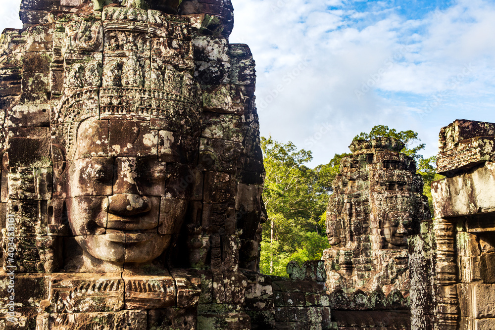 Portrait of a Face tower in the Bayon temple in Angkor with forest background. Cambodia. Horizontal view.