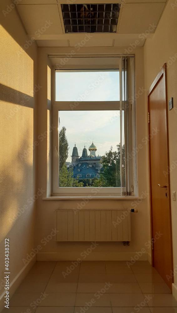 Through the closed large window you can see the domes of the church, trees and towers of the building Through the closed large window you can see the domes of the church, trees and towers of the building