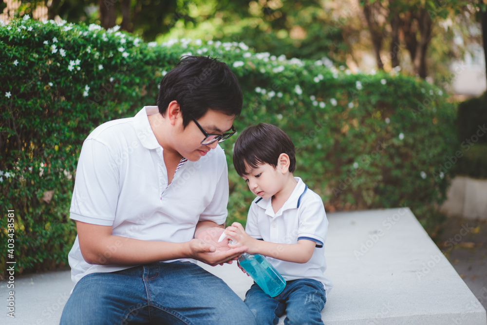 Little boy applying a liquid hand sanitizer or alcohol gel on his father's hands. Little boy applying a liquid hand sanitizer or alcohol gel on his father's hands.