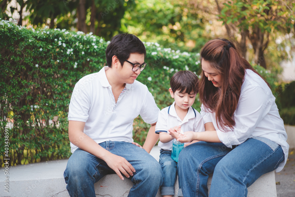 little boy pouring a liquid alcohol gel or hand sanitizer on his mother and father hands. little boy pouring a liquid alcohol gel or hand sanitizer on his mother and father hands.