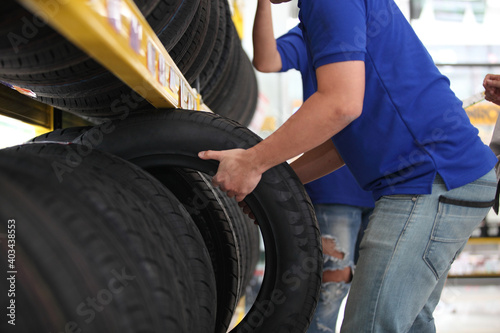 Salesman with showing wheel tires at car repair service or auto store, business, maintenance and people concept