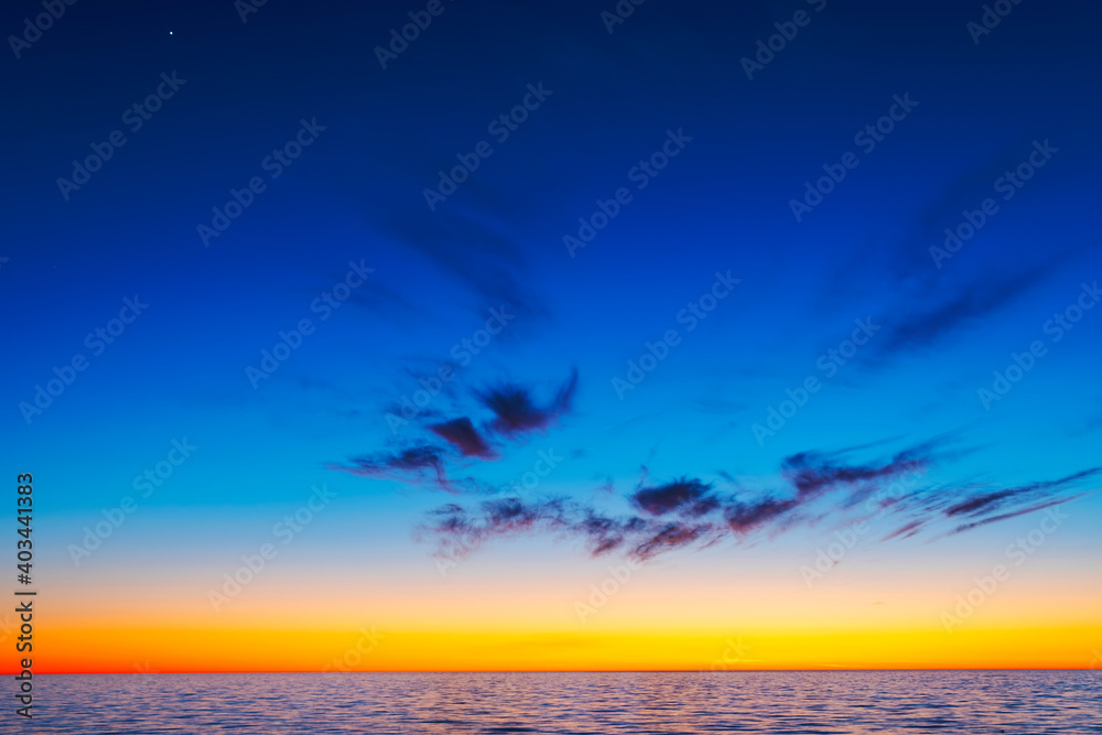 Vibrant colored spring sunset reflecting in ocean with endless horizon and deep blue ocean at island of Gotland in Sweden