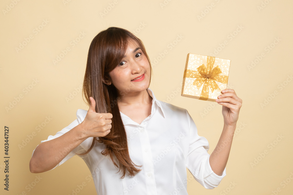 Young Asian woman thumbs up with a gift box. Young Asian woman thumbs up with a gift box.