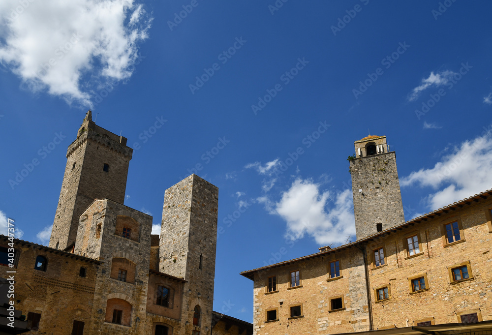 Low-angle view of the historic centre of San Gimignano, Unesco World Heritage Site, with the medieval towers Torre Grossa, Torri degli Ardinghelli and Torre Rognosa against blue sky, Tuscany, Italy