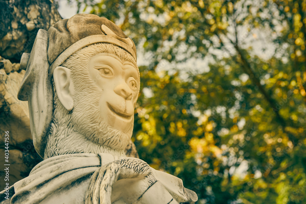 Phayao, Thailand - Nov 29, 2020: Zoom View Marble Sun Wukong or Monkey King Statue on Stone on Left Frame with Forest Background in Vintage Tone Phayao, Thailand - Nov 29, 2020: Zoom View Marble Sun Wukong or Monkey King Statue on Stone on Left Frame with Forest Background in Vintage Tone