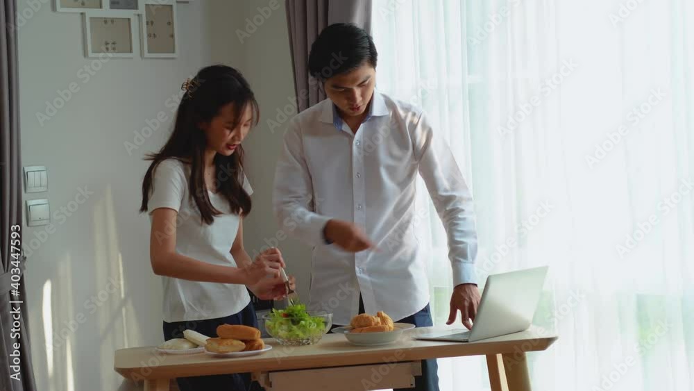Young Joyful Couple Cooking Healthy Vegetable Salad, Watching tutorial video for recipe on laptop, Laughing and Having Fun in the Kitchen Young Joyful Couple Cooking Healthy Vegetable Salad, Watching tutorial video for recipe on laptop, Laughing and Having Fun in the Kitchen
