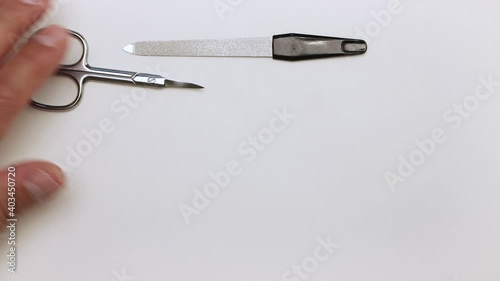 We put scissors, clipper, extractor, nippers, nail files on the table. Demonstration of tools for manicure. Items for work on a light surface. Professional hand care. Isolated video.