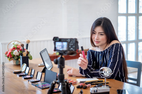 Young asian woman blogger with makeup cosmetics recording video at home.