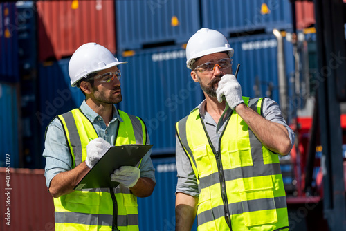 Obraz na płótnie Logistics engineer and inspector working togetter and discussing in shipping containerin commercial transport port w salonie