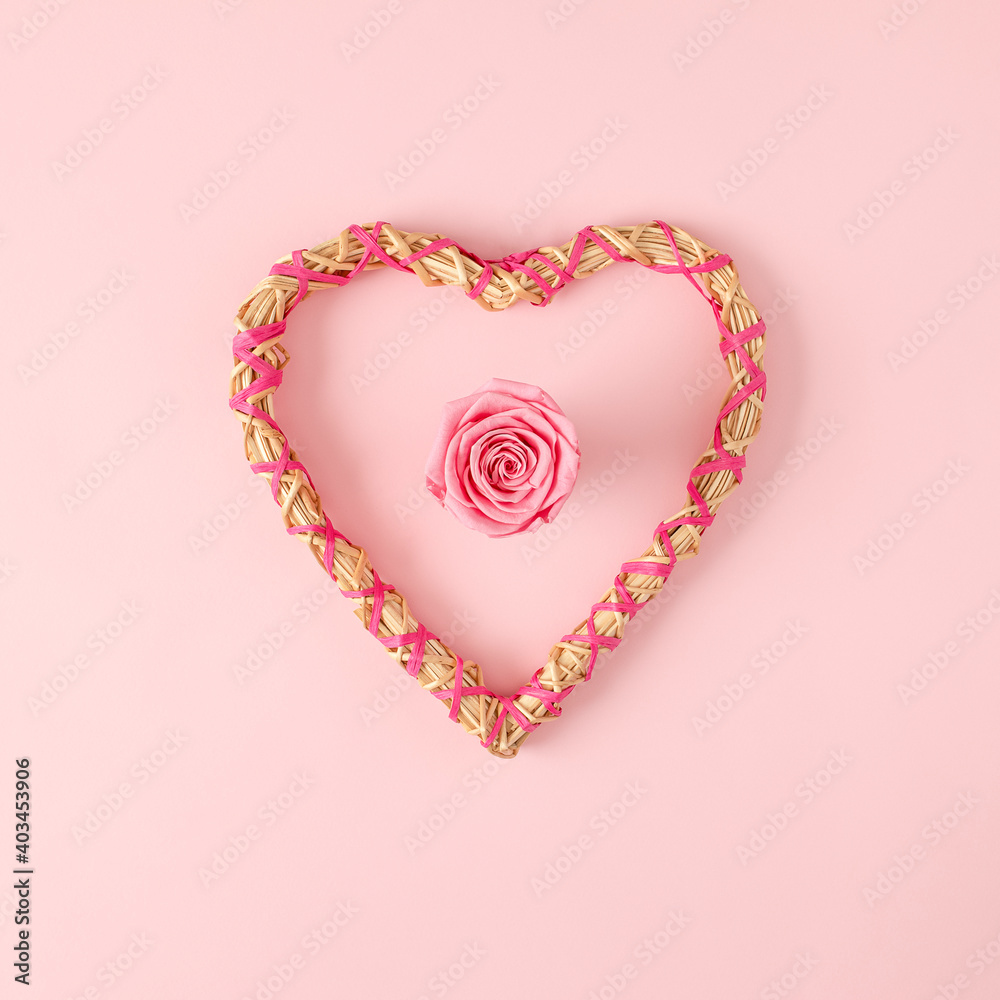 Heart shape frame made of straw with pink rose in center. Valentine's day flat lay concept.