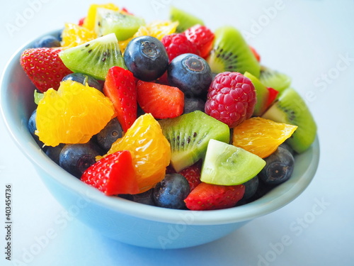 Fruit salad in a bowl on white background (kiwi, orange, strawberry, blueberry)