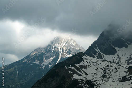 A panoramic view on the Alpine peaks in Austria from Marstein. The slopes are mostly covered with snow. Stony and sharp mountains. Overcast. Baren slopes, green valley below. Serenity and calmness © Chris