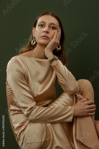 Fashion studio shot of woman in beige silk satin dress
