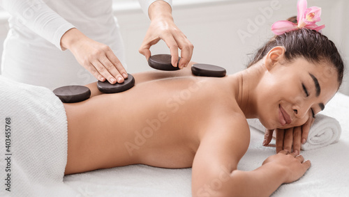 Relaxed Young Korean Lady Having Hot Stones Massage Session In Spa Salon