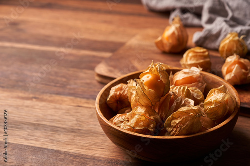 concept of cape gooseberry or physalis berry in a wooden bowl on a dining table in homemade style background with copy space 