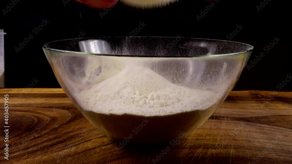 Sifting flour through a sieve into a glass bowl in the kitchen. Sifting flour through a sieve into a glass bowl in the kitchen.
