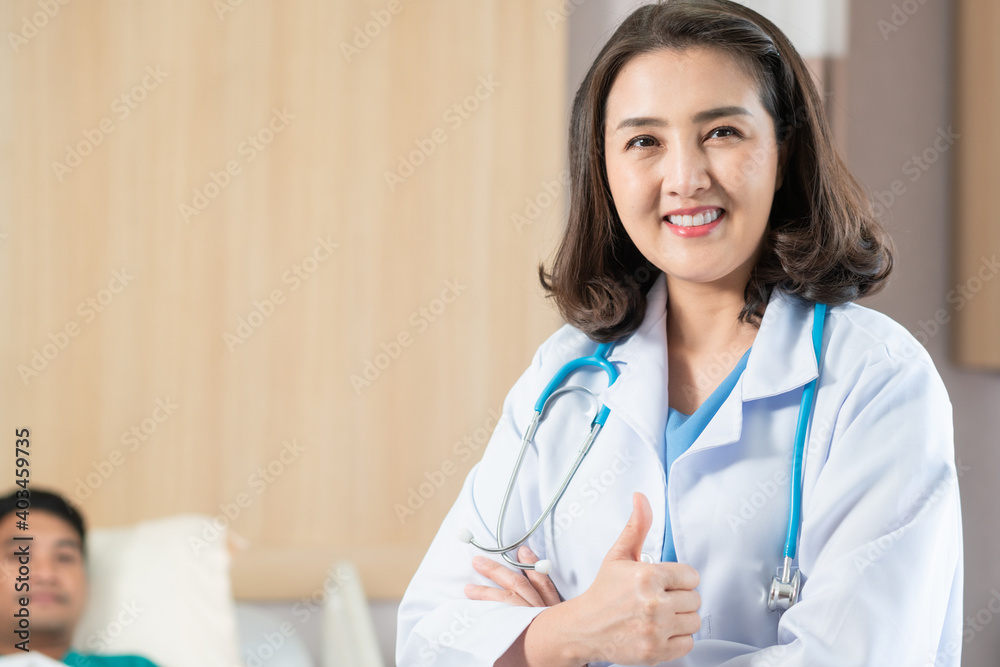 Portrait of Asian female doctor showing thumb up looking at camera in arm crossed. in hospital ward. copy space Portrait of Asian female doctor showing thumb up looking at camera in arm crossed. in hospital ward. copy space