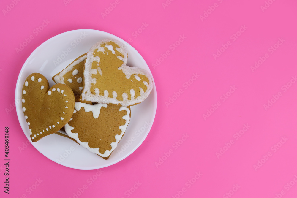 Gingerbread cookies hearts in a white plate on a pink background Gingerbread cookies hearts in a white plate on a pink background