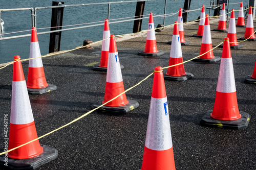 Close up of large number of traffic cones lined up on a harbour wall. photo